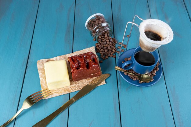 Guaiava dolce con formaggio su carta marrone circondata da posate in grani e una tazza di caffè