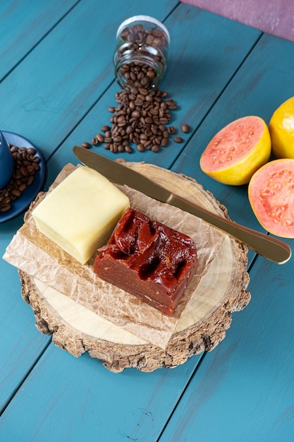 Guaiava dolce con formaggio su una tavola di legno accanto a una tazza e chicchi di caffè e coltello verticale