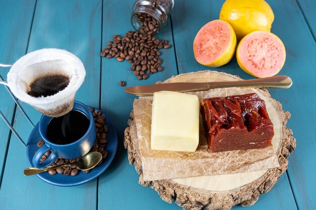 Guaiava dolce con formaggio su una tavola di legno accanto a una tazza e chicchi di caffè e coltello