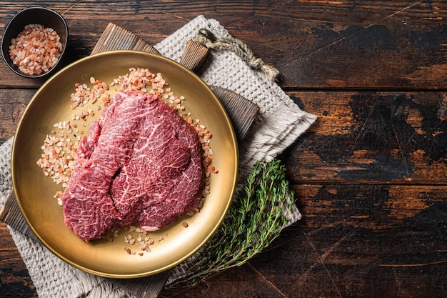 Guance di manzo carne di vitello cruda in lamiera d'acciaio con sale rosa Sfondo in legno Vista dall'alto Spazio di copia