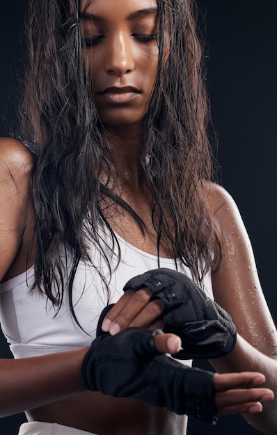 Guanti boxer e sudore con una donna sportiva che si prepara in studio su uno sfondo nero per il fitness Esercizio fisico e allenamento con un'atleta di boxe femminile che suda durante un allenamento di combattimento