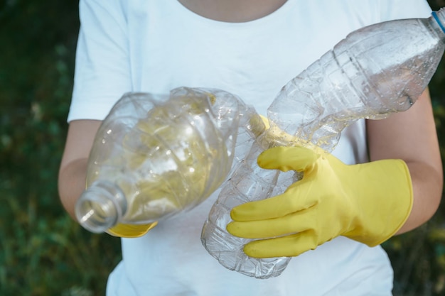 Guanti d'uso femminili che tengono le bottiglie di plastica riciclabili - concetto di plastica di inquinamento