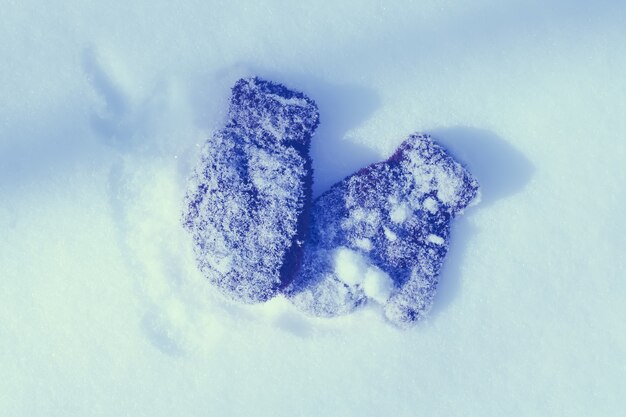 Guanti da bambino marrone caldo sulla superficie della neve.