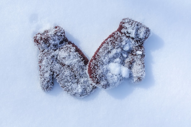 Guanti da bambino marrone caldo sulla superficie della neve.