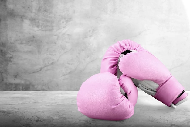 Guanti da boxe rosa sportivi per la ragazza sulla scrivania.