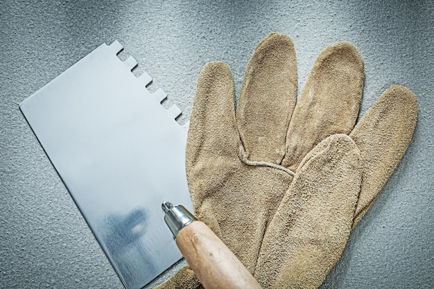 Guanti da lavoro per cazzuola per muratura su fondo in cemento.