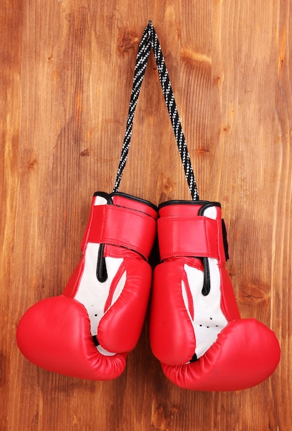 Guanti di boxe rossi appesi su uno sfondo di legno