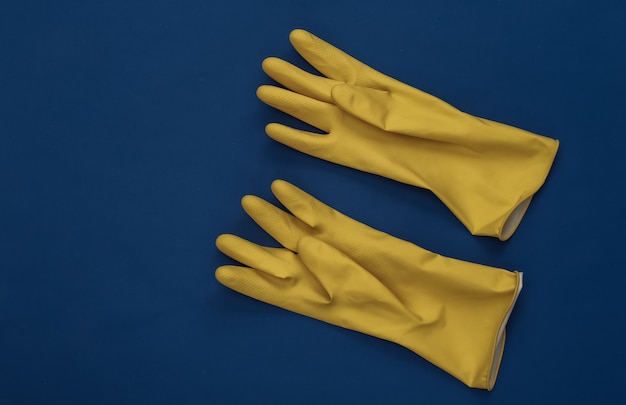 Guanti di gomma gialli su sfondo blu classico. Colore 2020. Tema per la pulizia della casa. Vista dall'alto