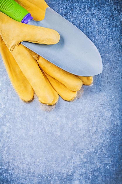 Guanti di sicurezza gialli pala a mano in metallo su fondo metallico concetto di giardinaggio