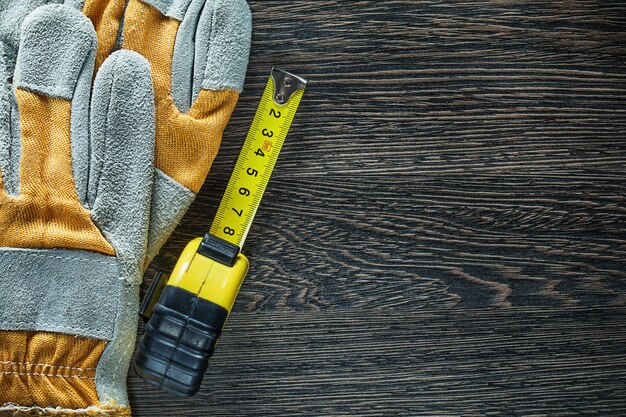 Guanti di sicurezza per metro a nastro arrotolato su tavola di legno