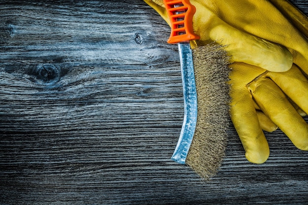 Guanti di sicurezza per spazzole metalliche a mano su tavola di legno vintage