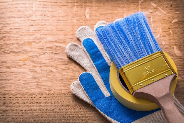 Guanti protettivi pennello e nastro adesivo su tavola di legno concetto di costruzione