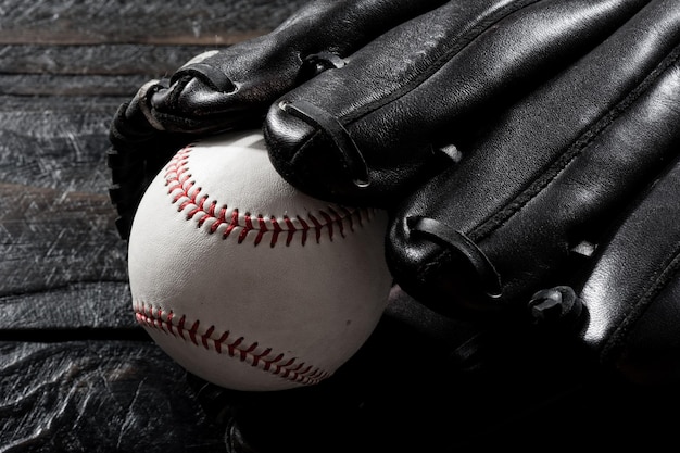 Guanto da baseball del primo piano e baseball sul concetto di sport di tema scuro del bordo di legno