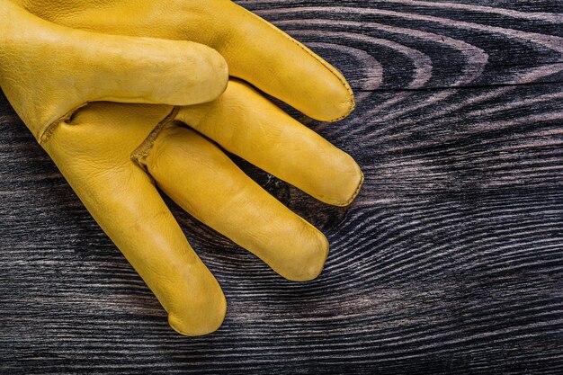 Guanto di sicurezza giallo in pelle su tavola di legno vintage concetto di costruzione