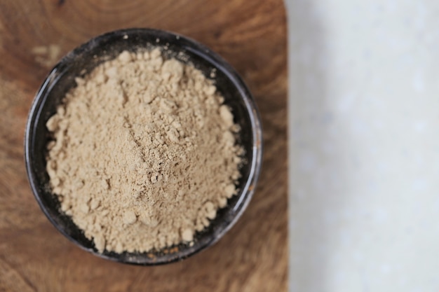 Guaranà in polvere in un piatto di ceramica su una tavola di legno su una superficie di marmo grigio.Natural energico. Porzione di polvere di guaranà. Foto di alta qualità