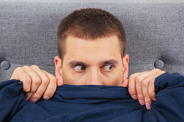 Guarda a destra un bel giovane nascosto dietro una coperta guarda da un lato direzione dello sguardo in direzioni diverse