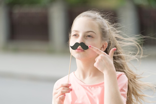 Guarda i miei baffi. Volto di sorriso felice dei capelli lunghi del capretto. Vacanze estive. Divertimento e umorismo. Ragazza bambino spensierato divertendosi. Bella giornata per divertirsi con gli oggetti di scena per cabine fotografiche. Felicità gioia e concetto di divertimento.