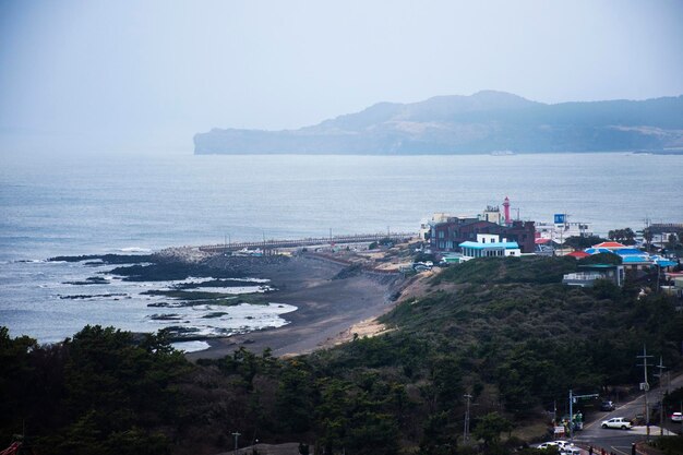 Guarda il paesaggio dell'isola di jeju e il paesaggio marino mare oceano con paesaggio urbano Seogwipo città al punto di vista per i viaggiatori coreani visita al tempio Sanbangsa il 18 febbraio 2023 a Jeju do Corea del Sud