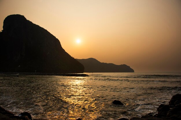 Guarda il paesaggio marino e l'onda nell'oceano marino con la montagna dell'isola mentre l'alba del mattino è l'ora dell'alba per i viaggiatori tailandesi che viaggiano visita riposano rilassati nella città di Khlong Wan a Prachuap Khiri Khan Thailandia