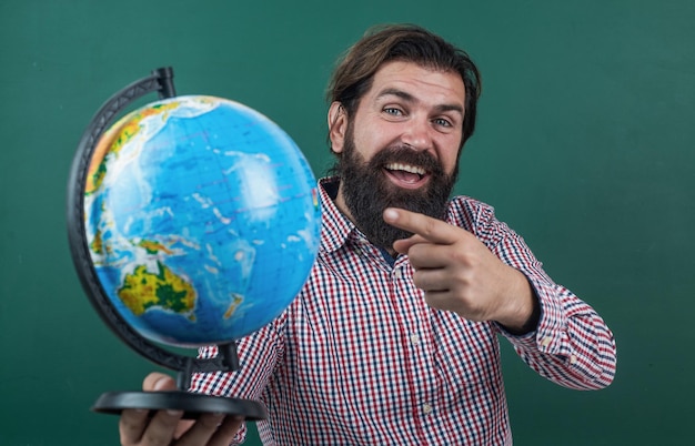 Guarda laggiù torna a scuola educazione informale felice insegnante maturo che punta al globo uomo barbuto geografo lavorare in classe con mappa prepararsi per esame docente universitario sulla lezione di geografia