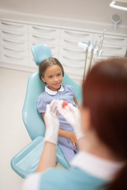 Guardando il dentista. Bella ragazza alla moda che esamina il suo dentista che prepara il paradenti