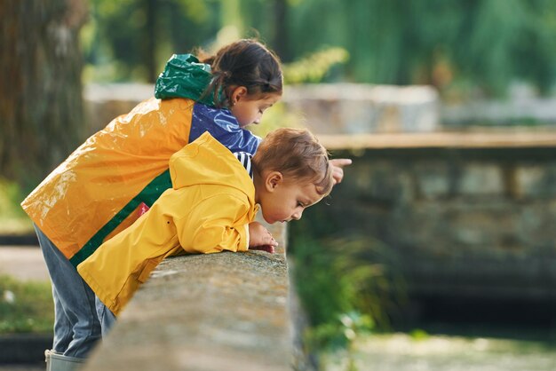 Guardando il fiume I bambini si divertono all'aperto nel parco dopo la pioggia