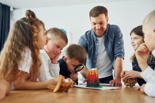 Guardando il modello del vulcano Gruppo di bambini studenti in classe a scuola con l'insegnante