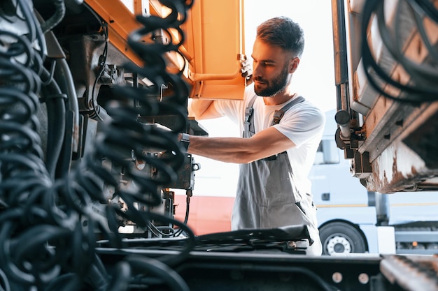 Guardando la connessione dei cavi Controllo di sicurezza Uomo in uniforme che fa servizio per un grosso veicolo di camion