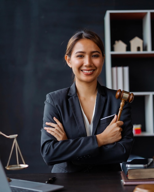 Guardando la fotocamera Giovane attraente avvocato asiatico femminile che lavora in ufficio con contratti e libri di legge quando è seduto alla scrivania Consulenza sui servizi legali di diritto Concetto di giustizia e immobiliare