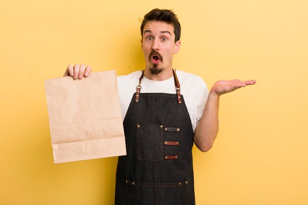 Guardando sorpreso e scioccato con la mascella caduta in possesso di un concetto di consegna di fast food oggetto