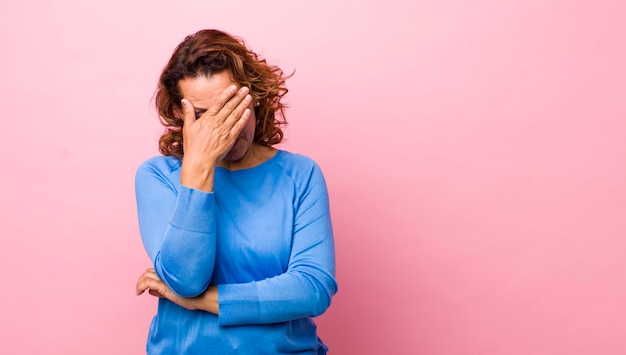 Guardando stressato vergognoso o sconvolto con un mal di testa che copre il viso con la mano