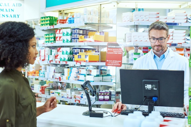 Guardando un'immagine ritagliata di un bel farmacista maschio maturo che aiuta una cliente femminile in farmacia