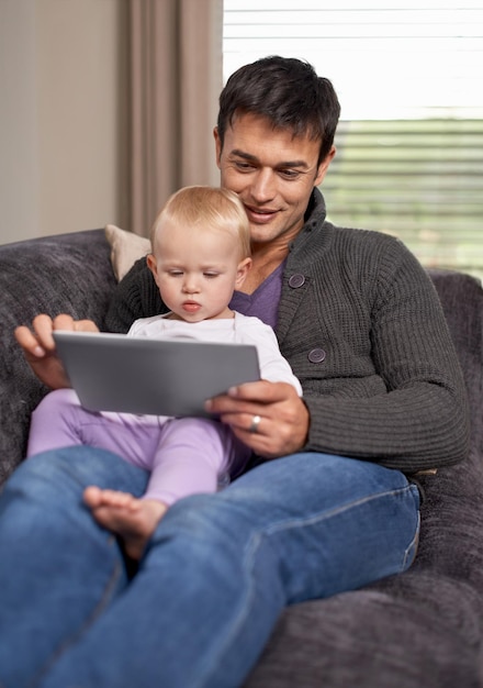 Guardare un cartone animato con papà Un giovane padre e sua figlia che giocano su una tavoletta digitale