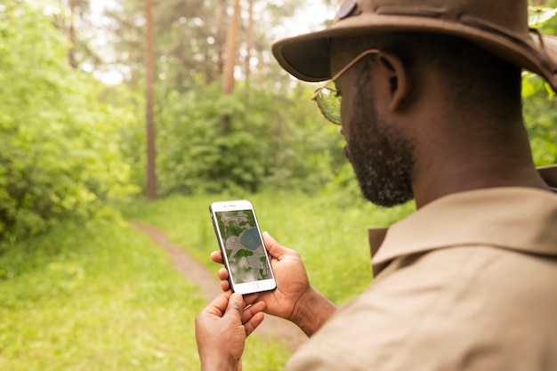 Guardiano forestale di vista laterale che tiene smartphone