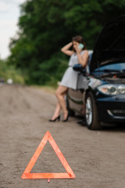 Guasto all'auto, segnale di arresto di emergenza, donna che chiede aiuto