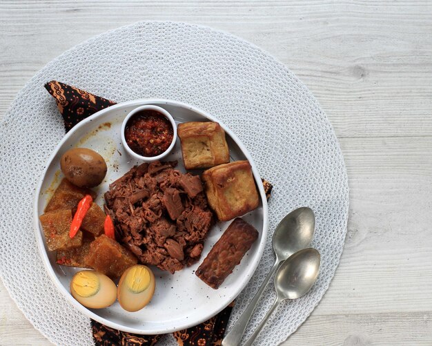 Gudeg. Un piatto iconico e leggendario di Yogyakarta in Indonesia. Stufato di Jack Fruit accompagnato con stufato piccante di cracker di pelle di bovino e uova marroni, tofu, tempeh e Sambal.