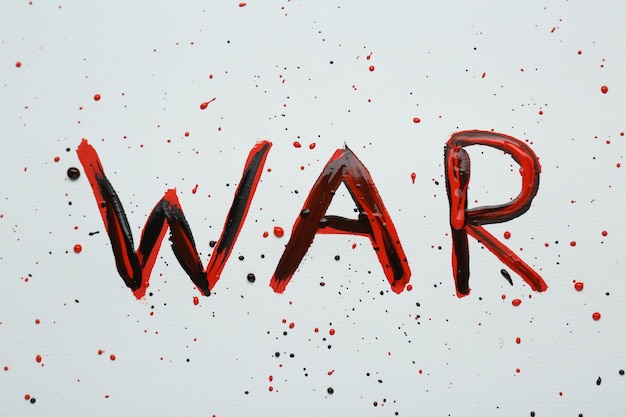 Guerra di parole scritta con vernice nera e rossa su sfondo bianco vista dall'alto