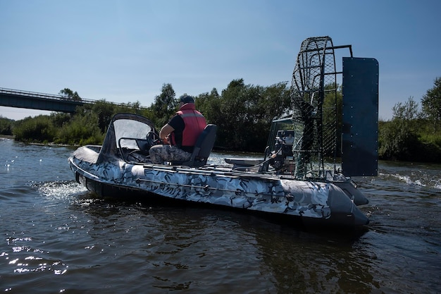 Guida ad alta velocità in un airboat sul fiume in una giornata estiva con spruzzi e onde