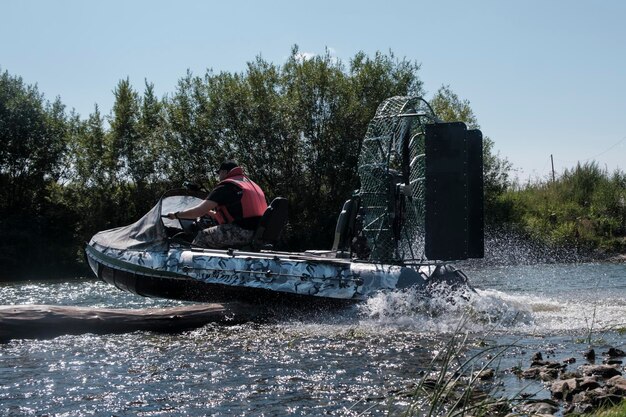 Guida ad alta velocità in un airboat sul fiume in una giornata estiva con spruzzi e onde