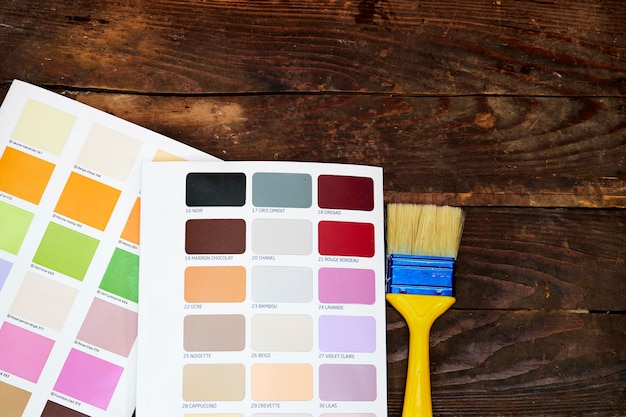 Guida alla palette di colori di campioni di vernice catalogo con pennello giallo-blu su tavolo di legno