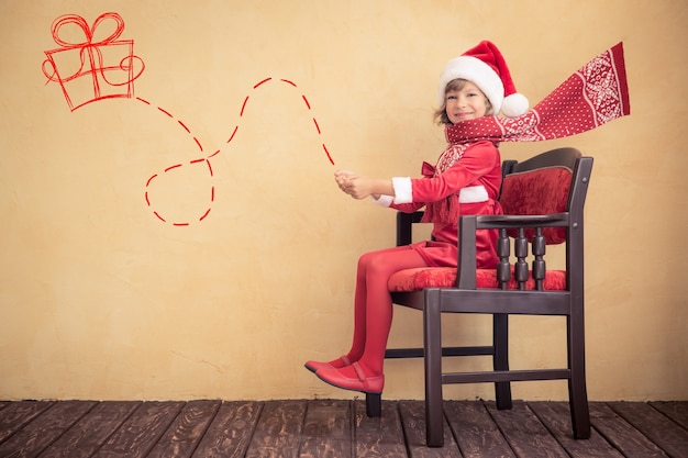 Guida felice del bambino nella slitta immaginaria di Babbo Natale. Concetto di miracolo di Natale