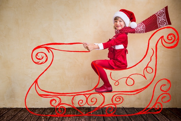 Guida felice del bambino nella slitta immaginaria di Babbo Natale. Concetto di miracolo di Natale