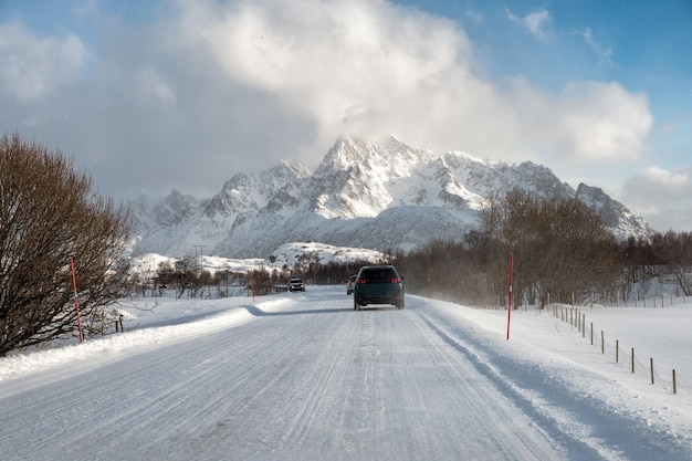 Guida in auto su strada innevata con montagna in campagna