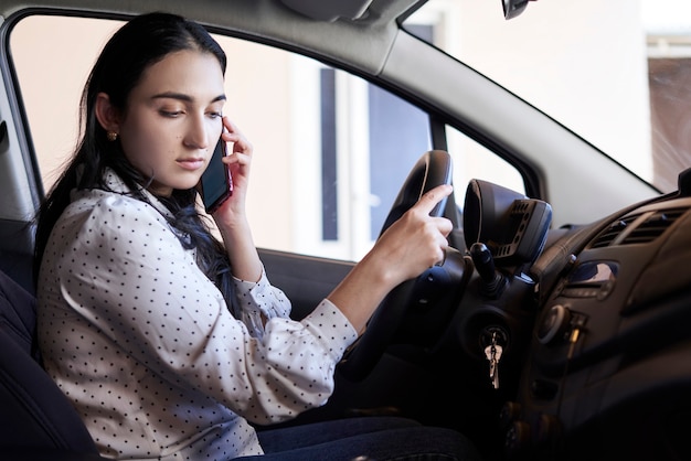 Guida non sicura giovane donna multirazziale che parla al telefono mentre guida una donna distratta alla guida