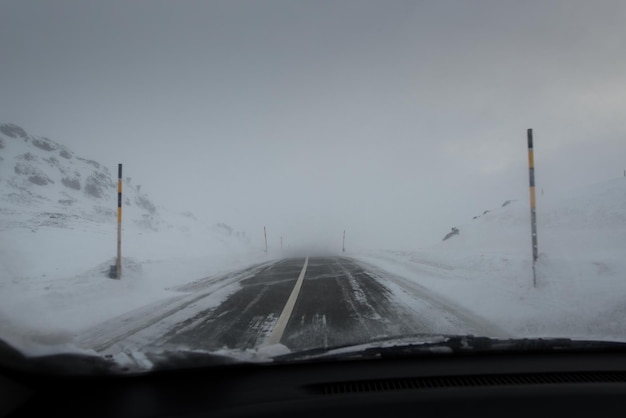 Guida su strada di montagna per auto con tempesta di neve