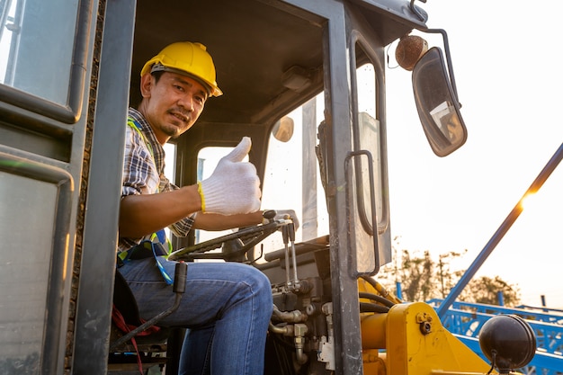 Guidando il trattore a ruote pesante del lavoratore, l'escavatore del caricatore della ruota con l'escavatore a cucchiaia rovescia che scarica la sabbia funziona nel cantiere.