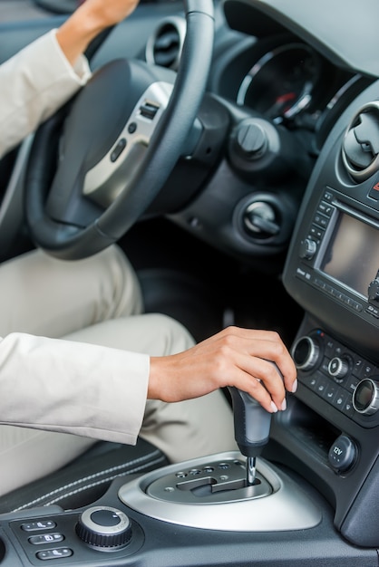 Guidando la sua nuova macchina. Primo piano di una donna in abiti da cerimonia alla guida di un'auto