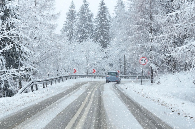 Guidare un'auto durante un brutto tempo invernale su una strada di montagna innevata