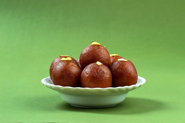 Gulab Jamun, dessert indiano condito con pistacchio nel piatto bianco su verde