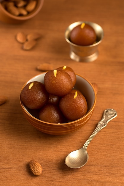 Gulab Jamun in ciotola e ciotola antica in rame con cucchiaio. Dessert indiano o piatto dolce.